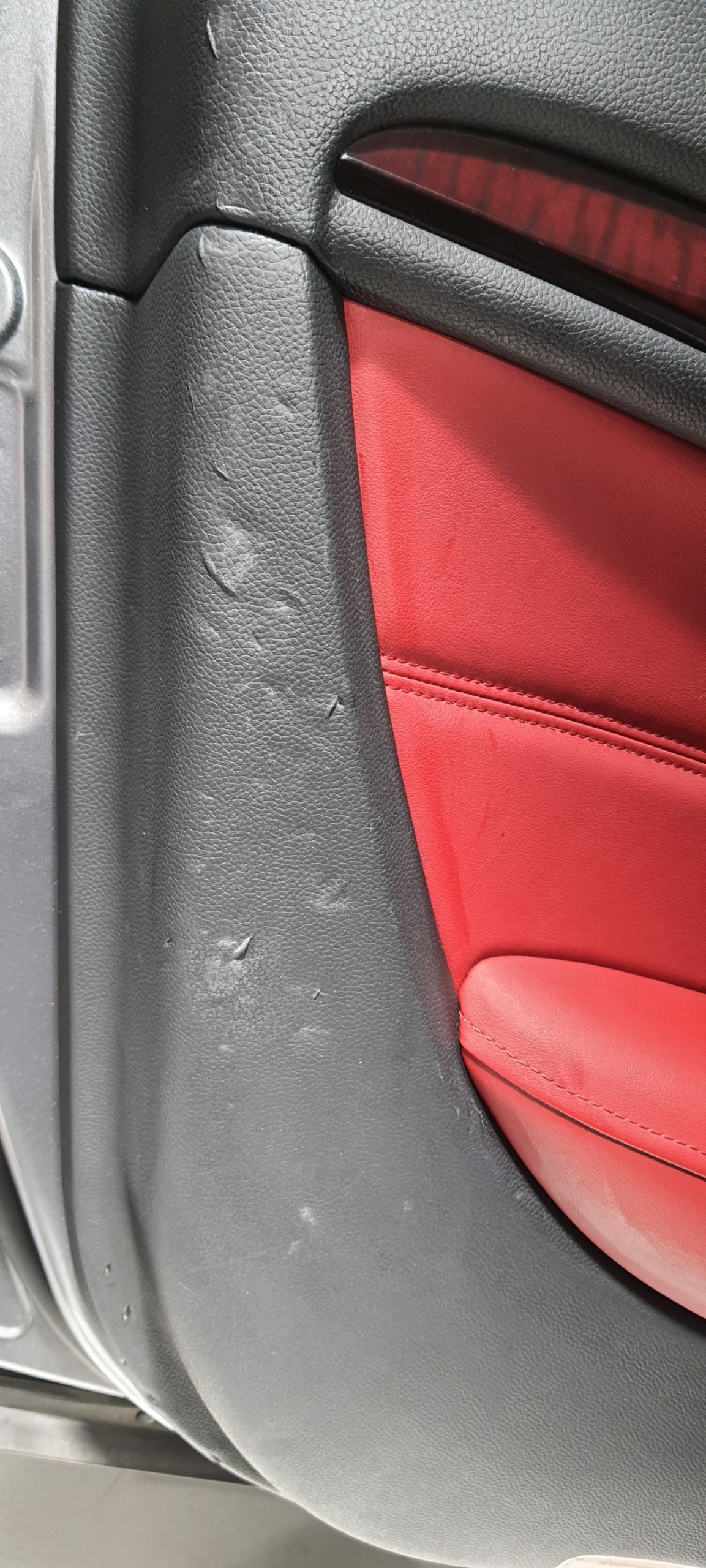 Réparation d'un panneau de porte d'Infinity Q35 Cabriolet, en cause de ces grosses éraflures et déchirements : La boucle de ceinture de sécurité mal enroulée et mal rangée dans son logement