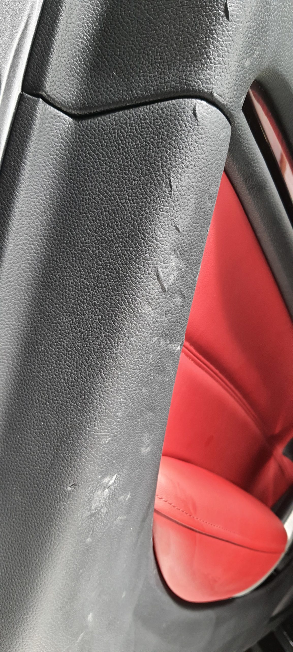 Réparation d'un panneau de porte d'Infinity Q35 Cabriolet, en cause de ces grosses éraflures et déchirements : La boucle de ceinture de sécurité mal enroulée et mal rangée dans son logement